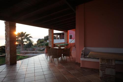 ein Esszimmer mit einem Tisch und Stühlen auf einer Terrasse in der Unterkunft Villa Artemis in Vathírrevma