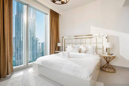 a bedroom with a large white bed with a large window at Luxurious 3 BR with Burj Khalifa View in Downtown in Dubai