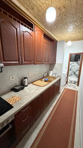 une cuisine avec des armoires en bois et un évier dans l'établissement Cozy Flat, à Tirana