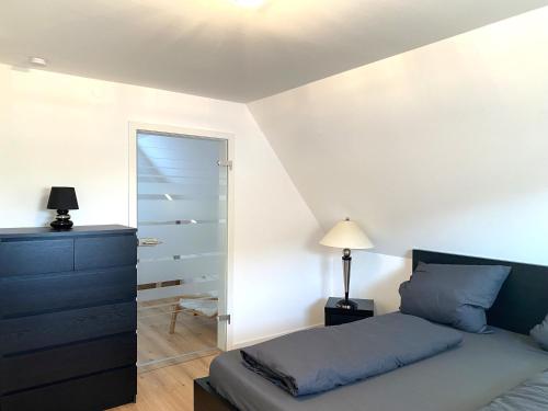 ein Schlafzimmer mit einem Bett, einer Kommode und einem Spiegel in der Unterkunft Modernes & zentral gelegenes Ferienhaus mit Garten und Parkplatz in Memmingen