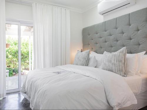 een witte slaapkamer met een groot bed met een groot hoofdeinde bij La Dolce Vita Gordon’s Bay in Gordonsbaai