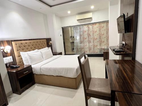 una camera d'albergo con un letto, una scrivania e una camera da letto di Grand Tulsi a Nānded