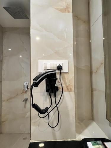a black phone is plugged into a wall in a bathroom at Grand Tulsi in Nānded
