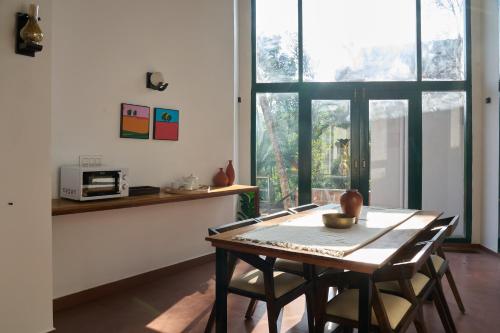a table and chairs in a room with a window at Nila by Raho - Secluded Villa with Estate View in Siddapur