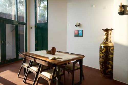 una mesa y sillas en una habitación con un jarrón en Notu by Raho - Secluded Villa with Estate View, en Siddapur