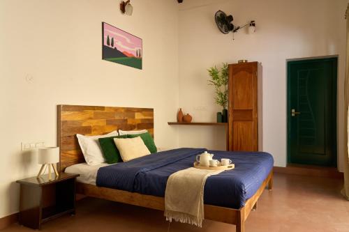 a bedroom with a bed with a blue comforter at Nila by Raho - Secluded Villa with Estate View in Siddapur