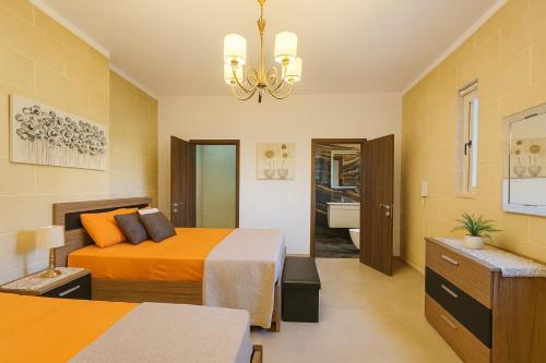 Un dormitorio con dos camas y una lámpara de araña. en Spacious Modern 3BR Oasis Villa with Private Pool, en Nadur