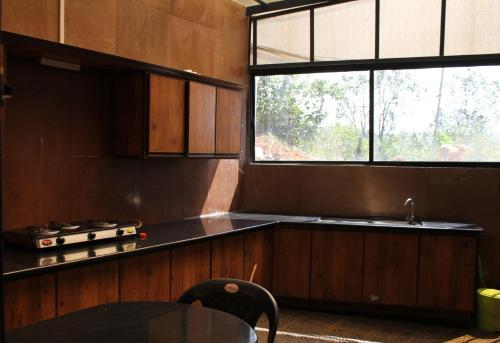 a kitchen with a table and a sink and a window at Kood Heritage cottages in Vagamon