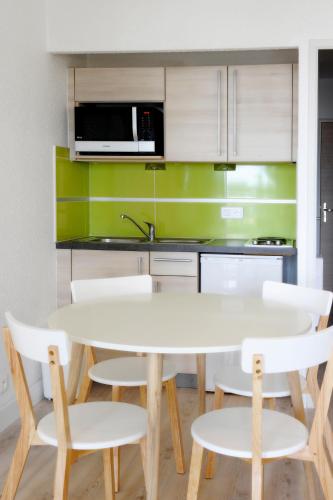 a kitchen with a white table and white chairs at Résidence de Tourisme l'Albatros in Palavas-les-Flots