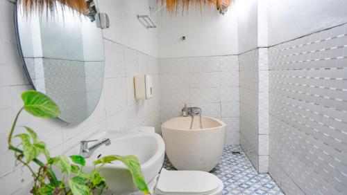 a white bathroom with a toilet and a sink at Sampai Villa Nayan in Yogyakarta