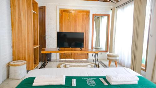 a bedroom with a bed and a desk with a television at Sampai Villa Nayan in Yogyakarta
