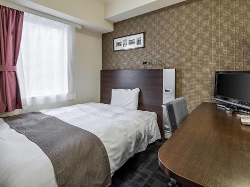 a hotel room with a bed and a desk with a computer at Comfort Hotel Suzuka in Suzuka