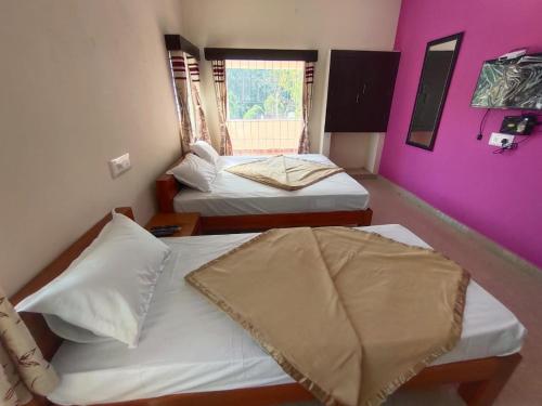 a room with two beds and a purple wall at Hiira Resort & homestay in Yercaud