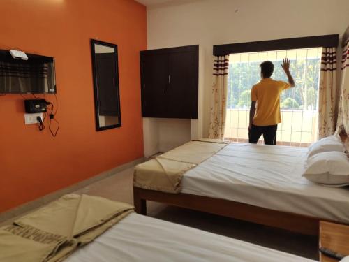 a man looking out of a window in a bedroom at Hiira Resort & homestay in Yercaud
