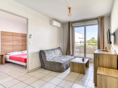 een slaapkamer met een bed, een bank en een raam bij Vacancéole - Résidence Cap Camargue in Le Grau-du-Roi