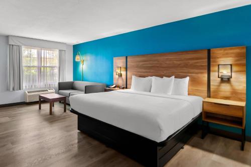 a hotel room with a large bed and a couch at Clarion Inn Falls Church-Arlington in Falls Church