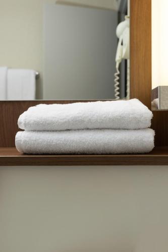 a stack of towels on a shelf in a bathroom at Campanile NATURE - Bordeaux Sud Pessac in Pessac