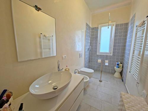 a white bathroom with a sink and a toilet at Villetta Tonfano in Marina di Pietrasanta