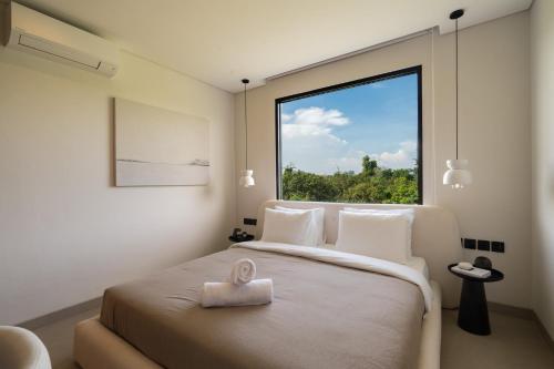 Zimmer mit einem großen Bett und einem großen Fenster in der Unterkunft Waves Bingin Luxury Apartments - Uluwatu by Yolla Hospitality in Bingin Beach