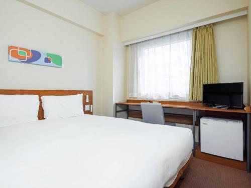 a hotel room with a large bed and a desk at Comfort Inn Chiba Hamano in Chiba