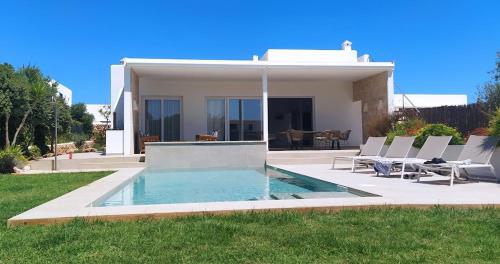a house with a swimming pool in the yard at VILLA PETRA ARENAL D'en CASTELL in Es Mercadal