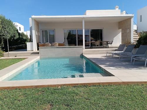a swimming pool in front of a house at VILLA PETRA ARENAL D'en CASTELL in Es Mercadal