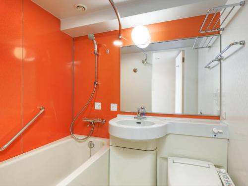 een oranje badkamer met een wastafel en een spiegel bij Comfort Inn Fukushima Nishi Inter in Fukushima