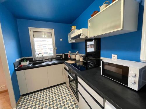 eine Küche mit blauen Wänden und einer schwarzen Arbeitsplatte in der Unterkunft Casino des fleurs in Vichy