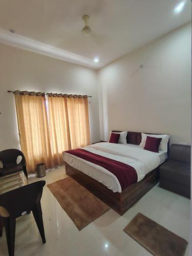 a bedroom with a bed and a chair and a desk at Nandin Guest House in Barkot