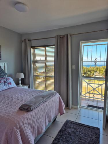 a bedroom with a bed and a large window at Villa Chanel Sea View in Mossel Bay