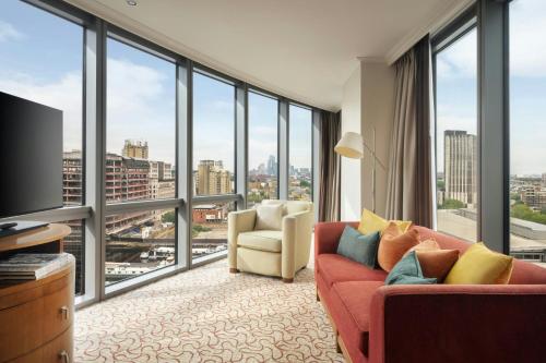 a living room with a couch and a large window at Marriott Executive Apartments London, Canary Wharf in London