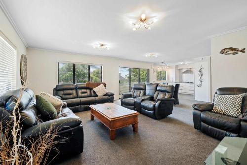 a living room with leather furniture and a table at Seven By The Sea - stylish apartment near port in New Plymouth