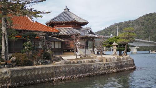 a building next to a body of water with a bridge at 萩市の静かな港町の一棟貸切宿 泊まれるカフェ 龍さん家 -Japanese traditional house- in Hagi