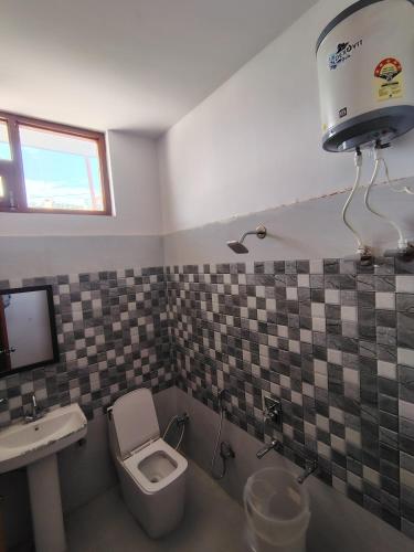 a bathroom with a toilet and a sink at Nandin Guest House in Barkot