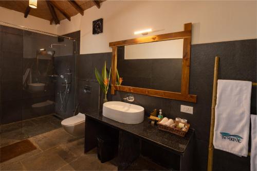 a bathroom with a sink and a toilet and a mirror at The Wave , Palolem in Canacona