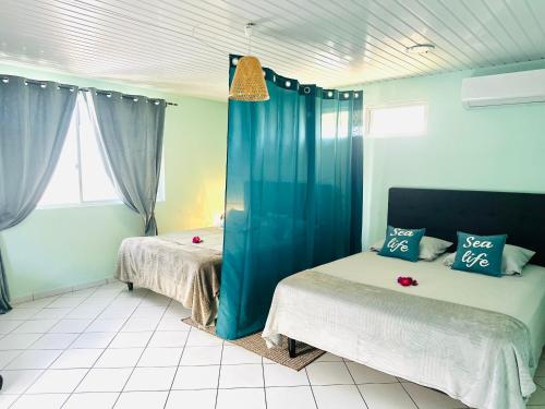 1 dormitorio con 2 camas y cortinas azules en Manahiti properties, en Moorea