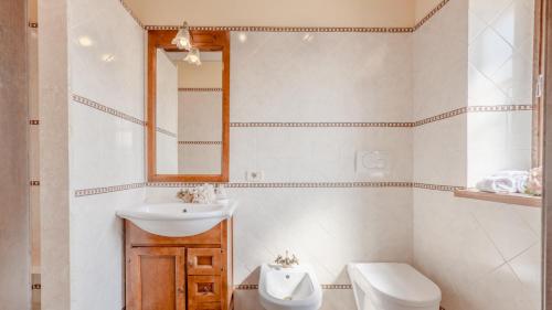 une salle de bain avec un lavabo, des toilettes et un miroir dans l'établissement LE MACINE 6, Emma Villas, à Castel del Piano