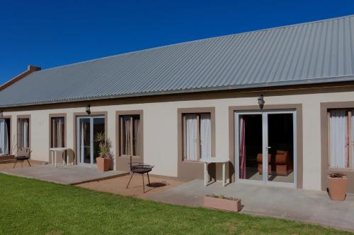 Una casa blanca con puertas de cristal y un patio. en Grünau Chalets, en Khomas Region
