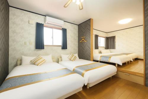 a hotel room with three beds in it at 糸島リトリートヴィラ芥屋 in Itoshima