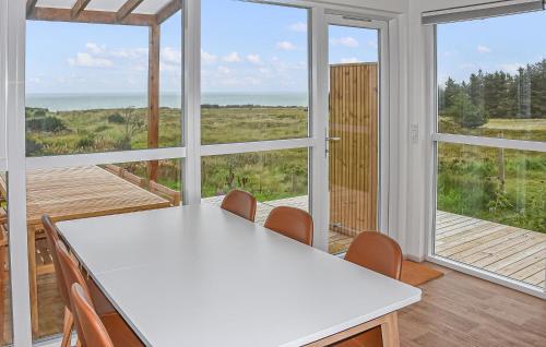 a kitchen with a white table and chairs and windows at 5 Bedroom Amazing Home In Hanstholm in Pugdal