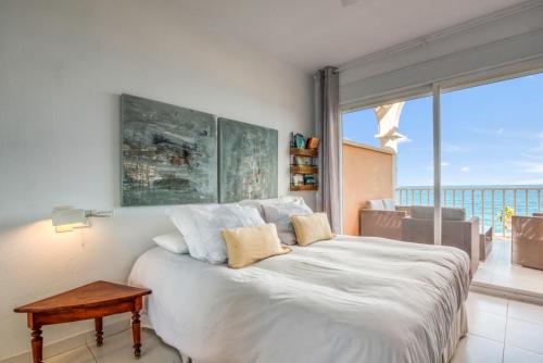 a bedroom with a large white bed and a large window at Jávea Beachfront Penthouse in Platja de l'Arenal