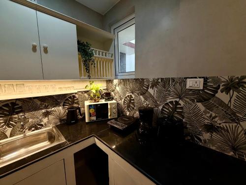 a kitchen with a sink and a microwave on a counter at Villa By The Beach Goa in Benaulim