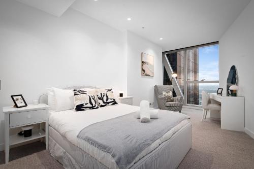 a white bedroom with a bed and a desk and a window at Brand New Luxury Stay with Garden View Same Tower as Ritz Carlton in Melbourne