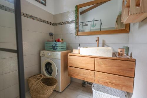 a bathroom with a washing machine and a sink at L Échappée Belle Havre de paix au cœur du verger in Le Moule