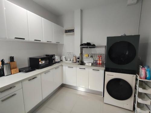 a kitchen with white cabinets and a black refrigerator at 88house suratthani in Suratthani