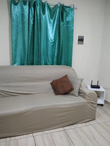 a couch in a room with a green curtain at Sobrado Frescor do Mar! in Cabo Frio