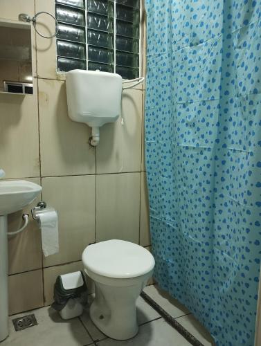 a bathroom with a toilet and a blue shower curtain at Sobrado Frescor do Mar! in Cabo Frio