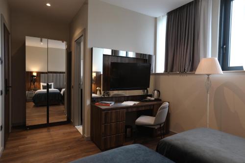 una camera da letto e una scrivania con TV. di White Hill Hotel a Tbilisi City