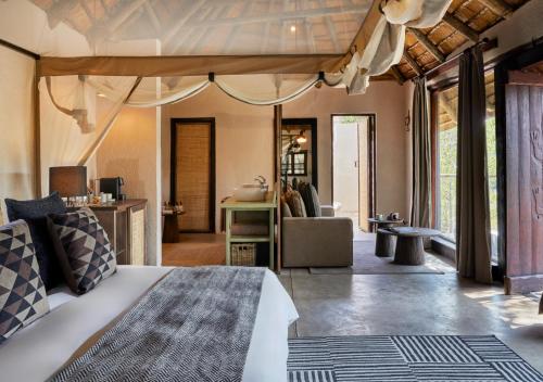 a bedroom with a bed and a living room at Toro River by NEWMARK in Makalali Game Reserve