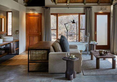 a living room with a couch and a bath tub at Toro River by NEWMARK in Makalali Game Reserve